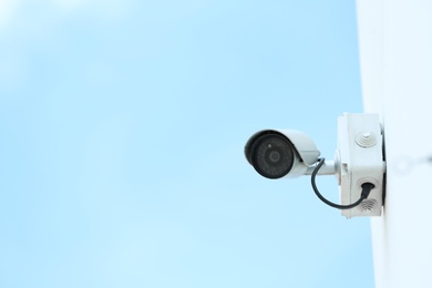 Photo of Modern CCTV security camera on building wall outdoors. Space for text