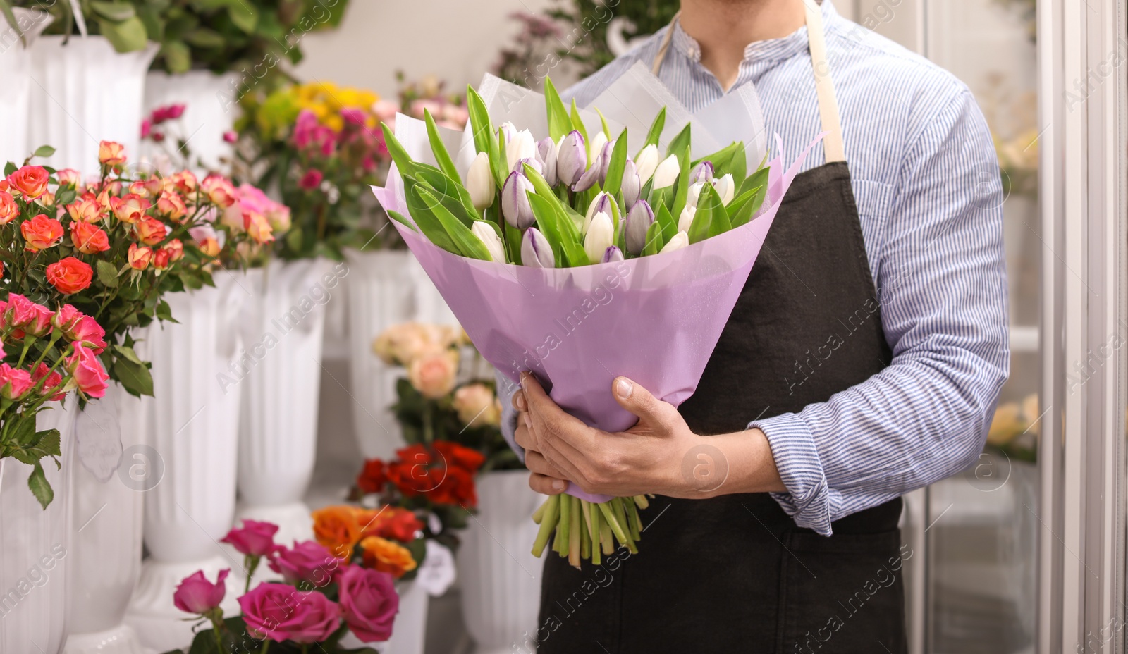 Photo of Male florist holding bouquet flowers at workplace