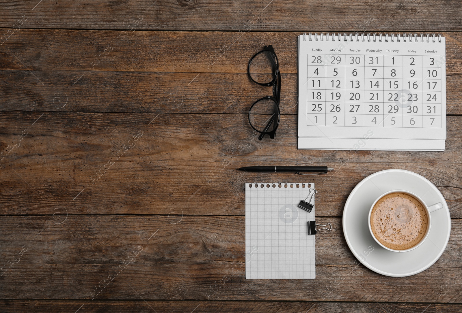 Photo of Flat lay composition with calendar and cup of coffee on wooden table. Space for text