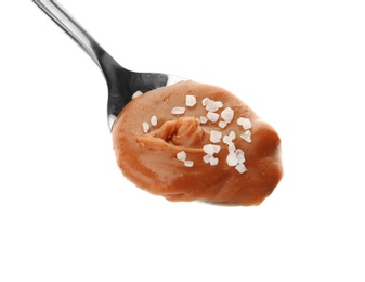 Spoon with delicious caramel and salt on white background