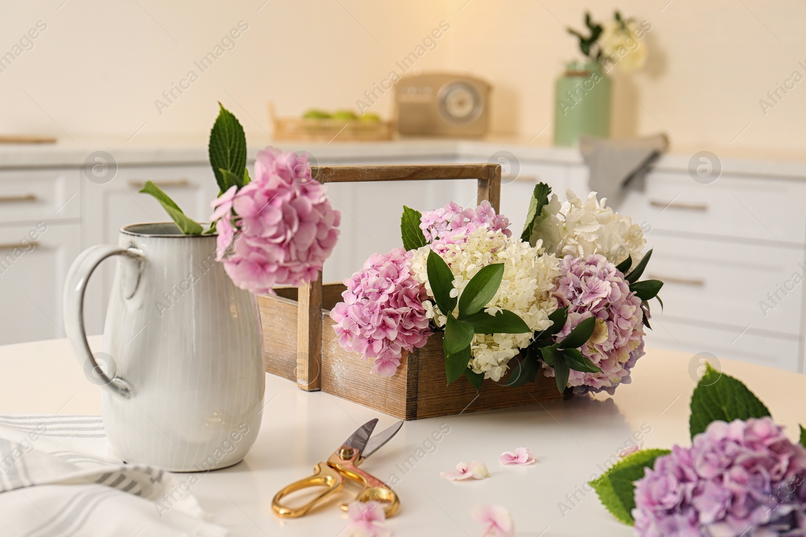 Photo of Beautiful hydrangea flowers and scissors on white table in kitchen. Interior design