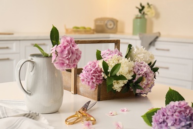 Beautiful hydrangea flowers and scissors on white table in kitchen. Interior design