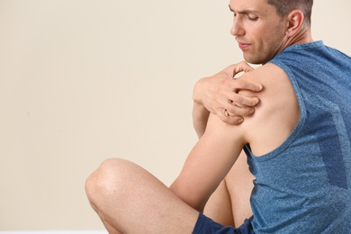 Photo of Man in sportswear suffering from shoulder pain on light background