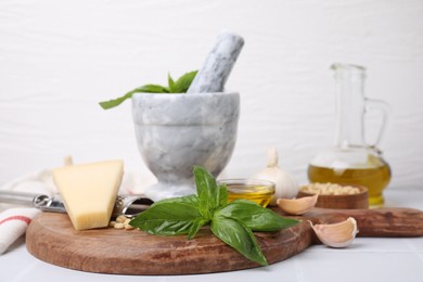 Different ingredients for cooking tasty pesto sauce on white table