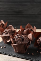 Delicious chocolate muffins on wooden table, closeup