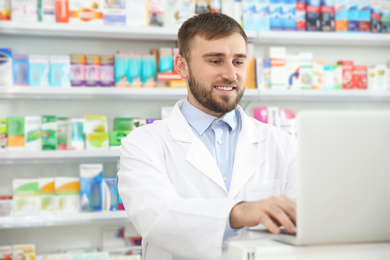 Image of Professional pharmacist working on laptop in modern drugstore