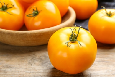 Photo of Ripe yellow tomato on wooden table, closeup