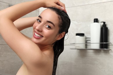 Beautiful happy woman washing hair in shower. Space for text