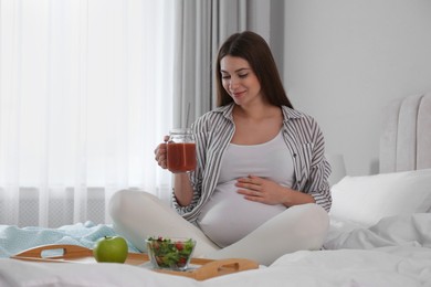 Photo of Pregnant woman eating breakfast on bed at home. Healthy diet