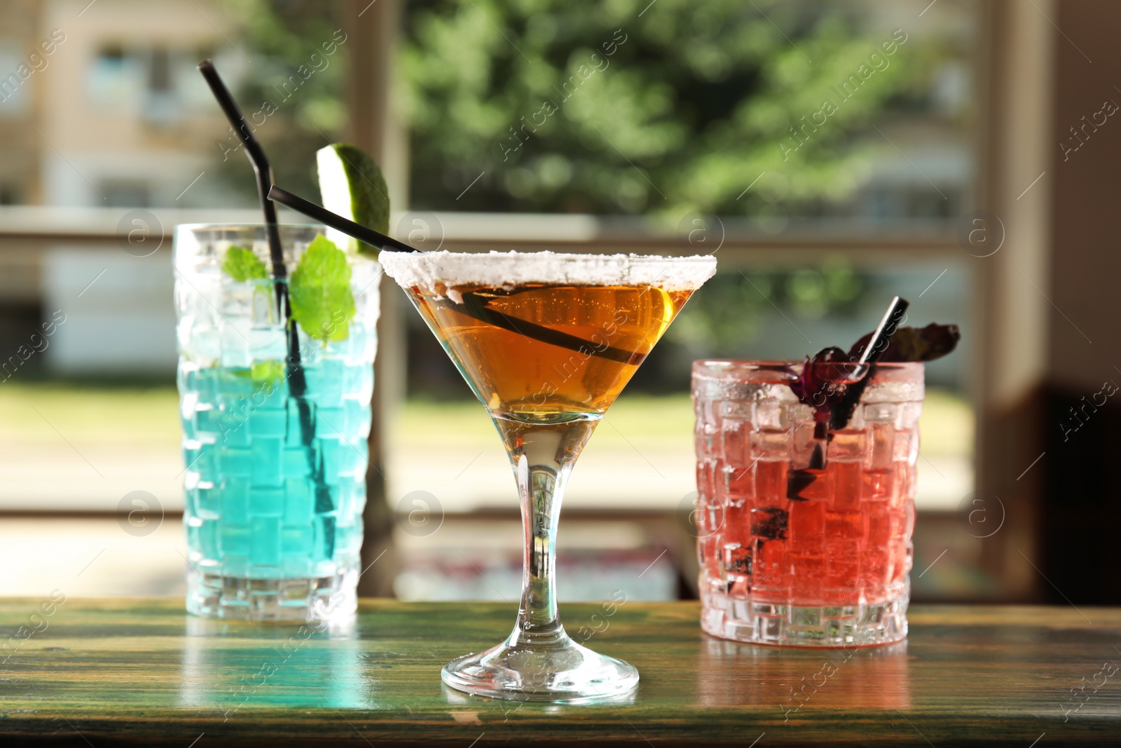 Photo of Glasses with delicious cocktails on counter in bar