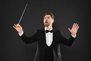 Photo of Professional conductor with baton on black background