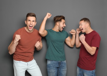 Group of friends celebrating victory against gray background