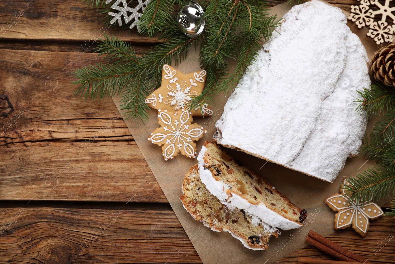 Photo of Traditional Christmas Stollen with icing sugar on wooden table, flat lay. Space for text