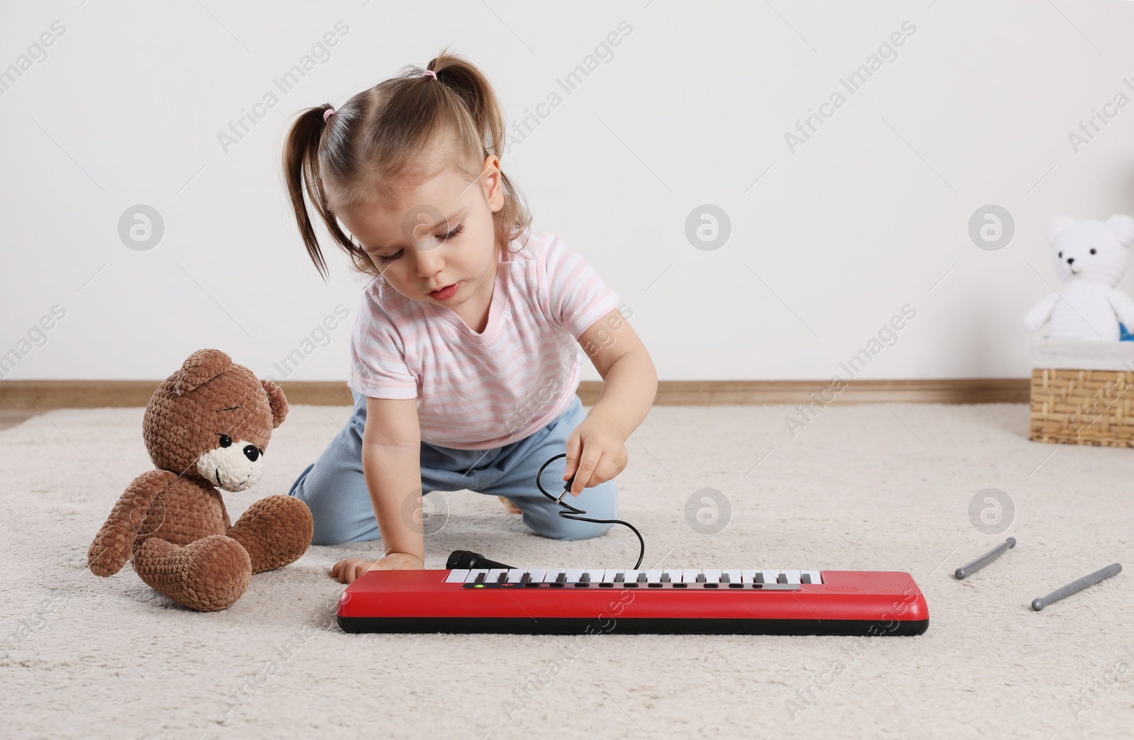 Photo of Cute little girl playing with toy piano at home