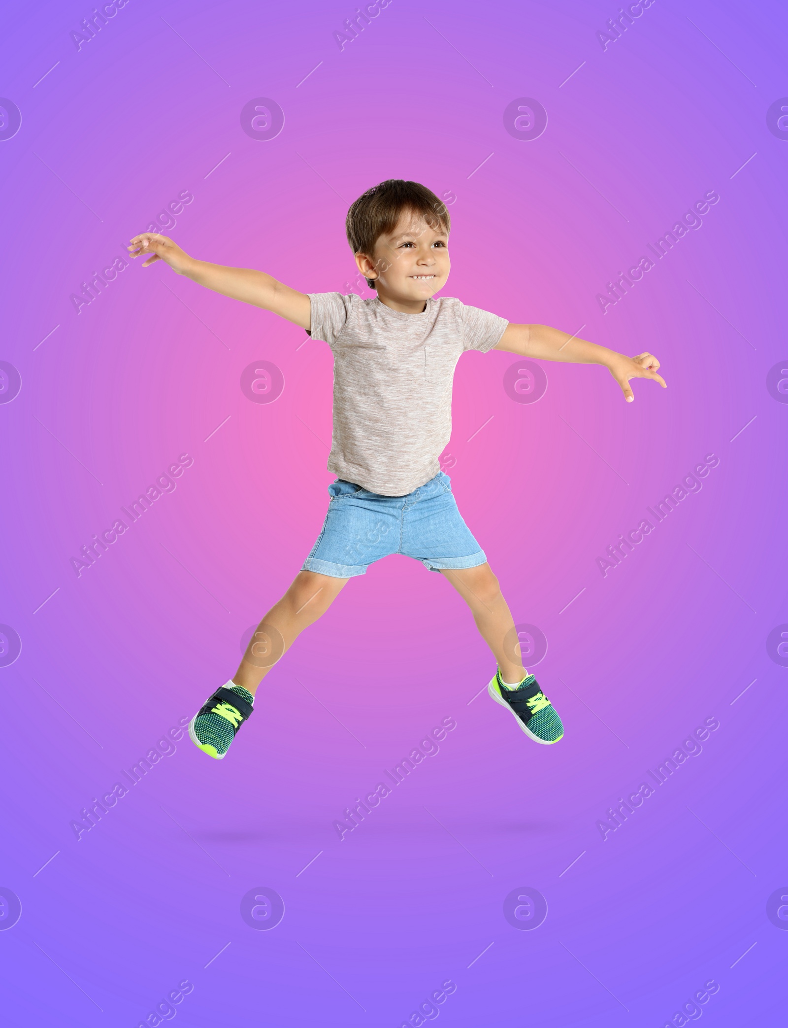 Image of Happy boy jumping on color gradient background