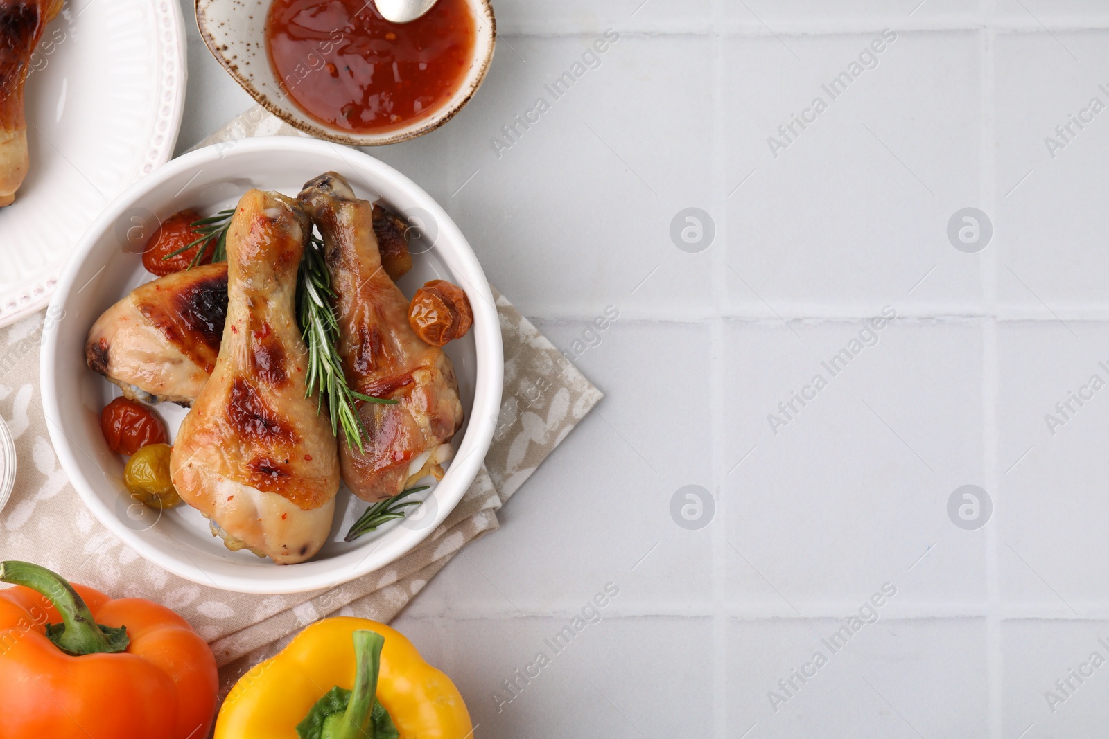 Photo of Marinade, roasted chicken drumsticks and other products on white tiled table, flat lay. Space for text