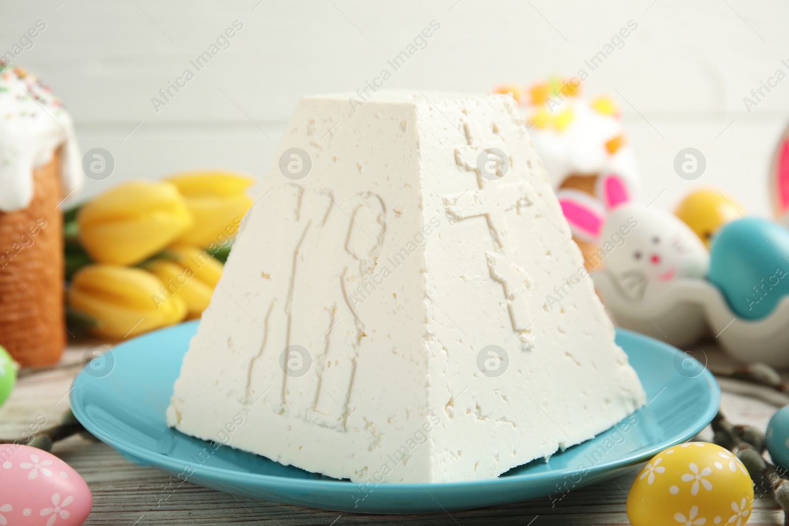 Photo of Traditional cottage cheese Easter paskha and dyed eggs on white wooden table, closeup