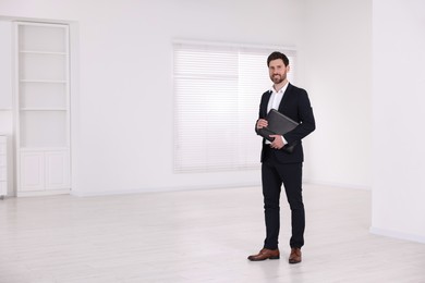Photo of Happy real estate agent with leather portfolio in new apartment