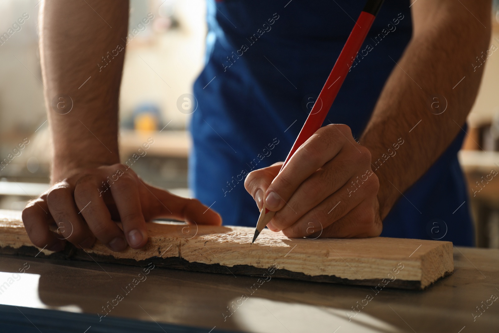 Photo of Professional carpenter making mark on wooden board in workshop, closeup