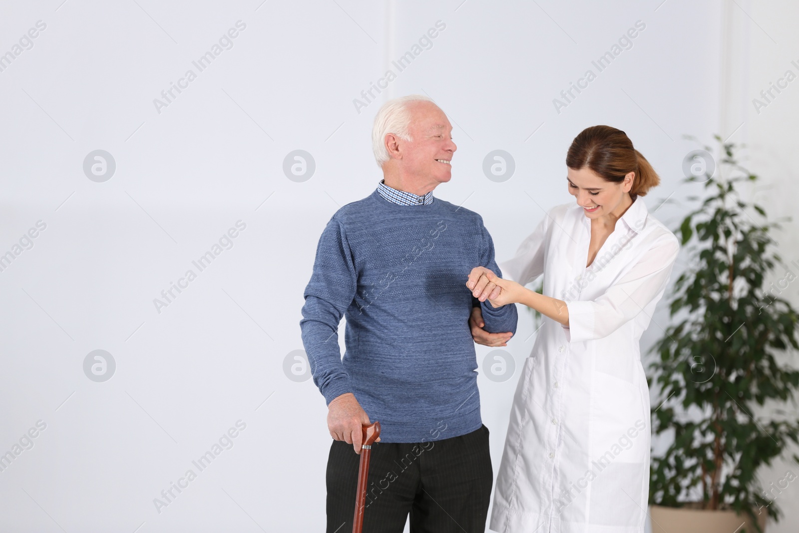 Photo of Elderly man with female caregiver indoors. Space for text