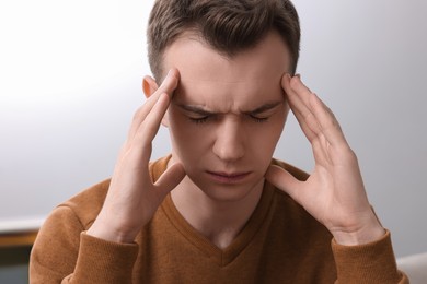 Sad man suffering from headache at home