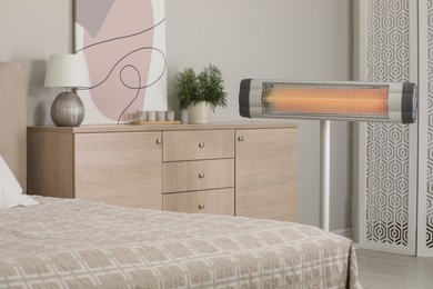 Photo of Modern electric infrared heater in cozy bedroom