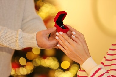 Man with engagement ring making proposal to his girlfriend against blurred lights, closeup