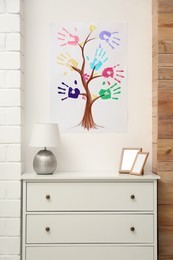 Photo of Family tree drawing with colorful palm prints on wall at home