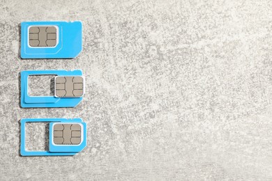 Photo of SIM cards on light grey stone background, flat lay. Space for text