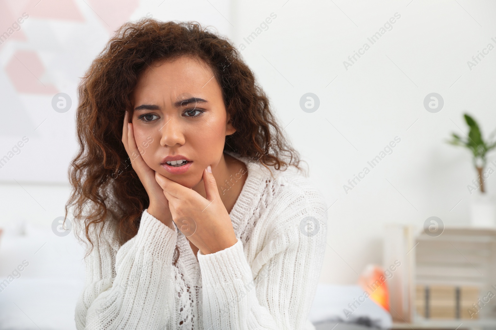 Photo of African-American woman suffering from tooth ache at home. Space for text