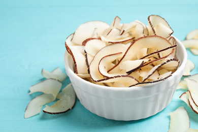 Photo of Tasty coconut chips on light blue wooden table