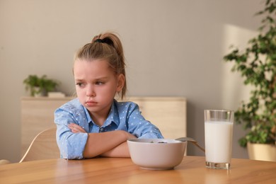 Photo of Cute little girl refusing to eat her breakfast at home