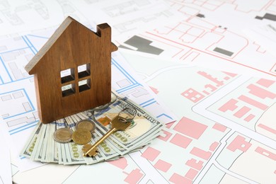 Photo of Money, key and wooden house model on cadastral maps