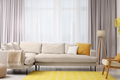 Photo of Spring atmosphere. Stylish room interior with comfy sofa, lamp, ottoman and armchair