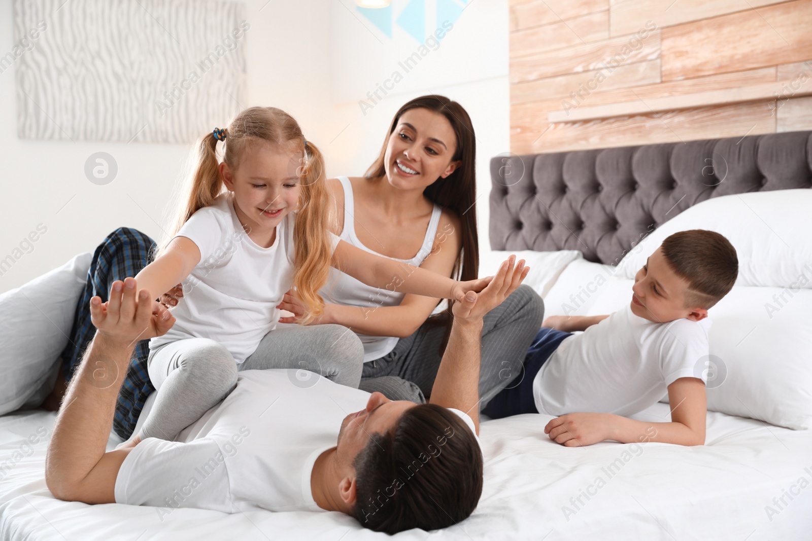 Photo of Happy young family together on large bed