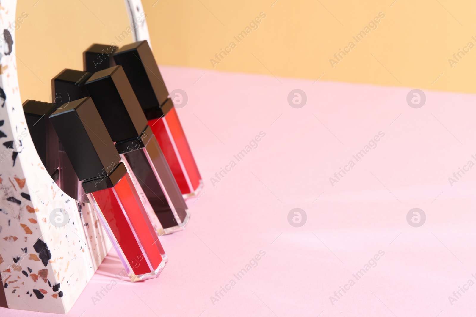 Photo of Different lip glosses and mirror on color background, space for text