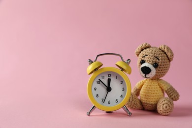 Photo of Alarm clock and toy bear on pink background, space for text. Time to give birth