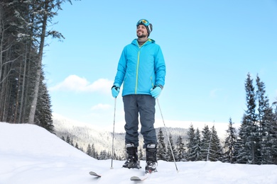 Man with ski equipment spending winter vacation in mountains