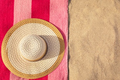 Photo of Beach towel and straw hat on sand, flat lay. Space for text