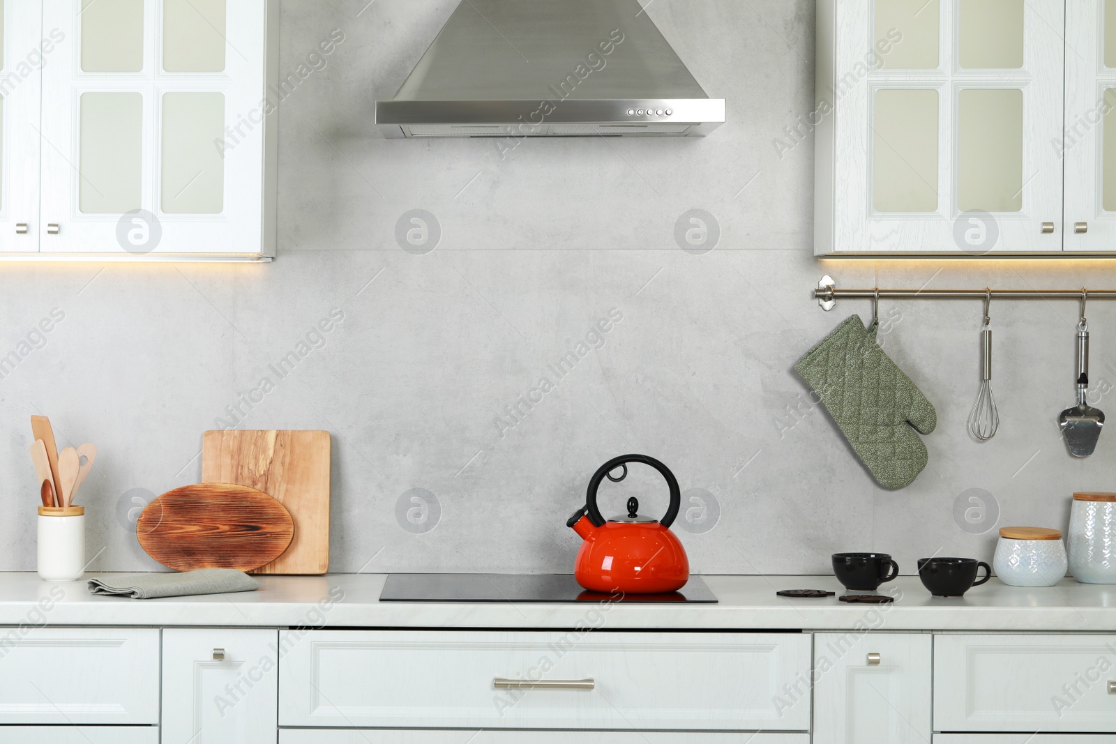 Photo of Red kettle with whistle on cooktop in kitchen