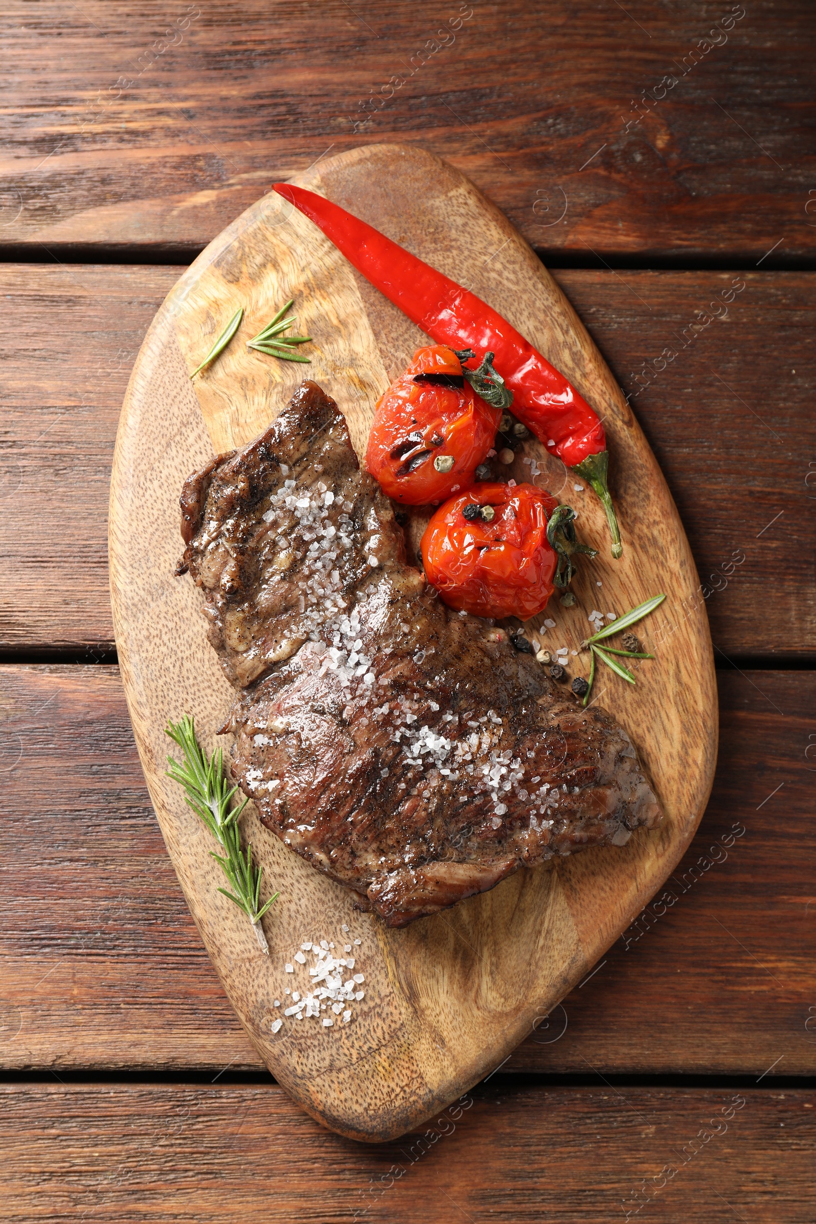 Photo of Delicious roasted beef meat, vegetables and spices on wooden table, top view