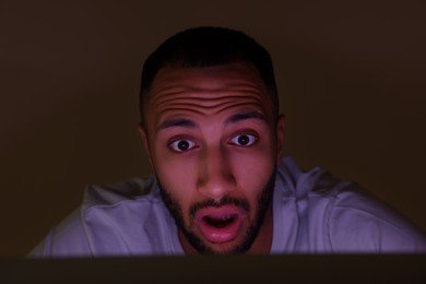 Shocked man using computer at night. Internet addiction