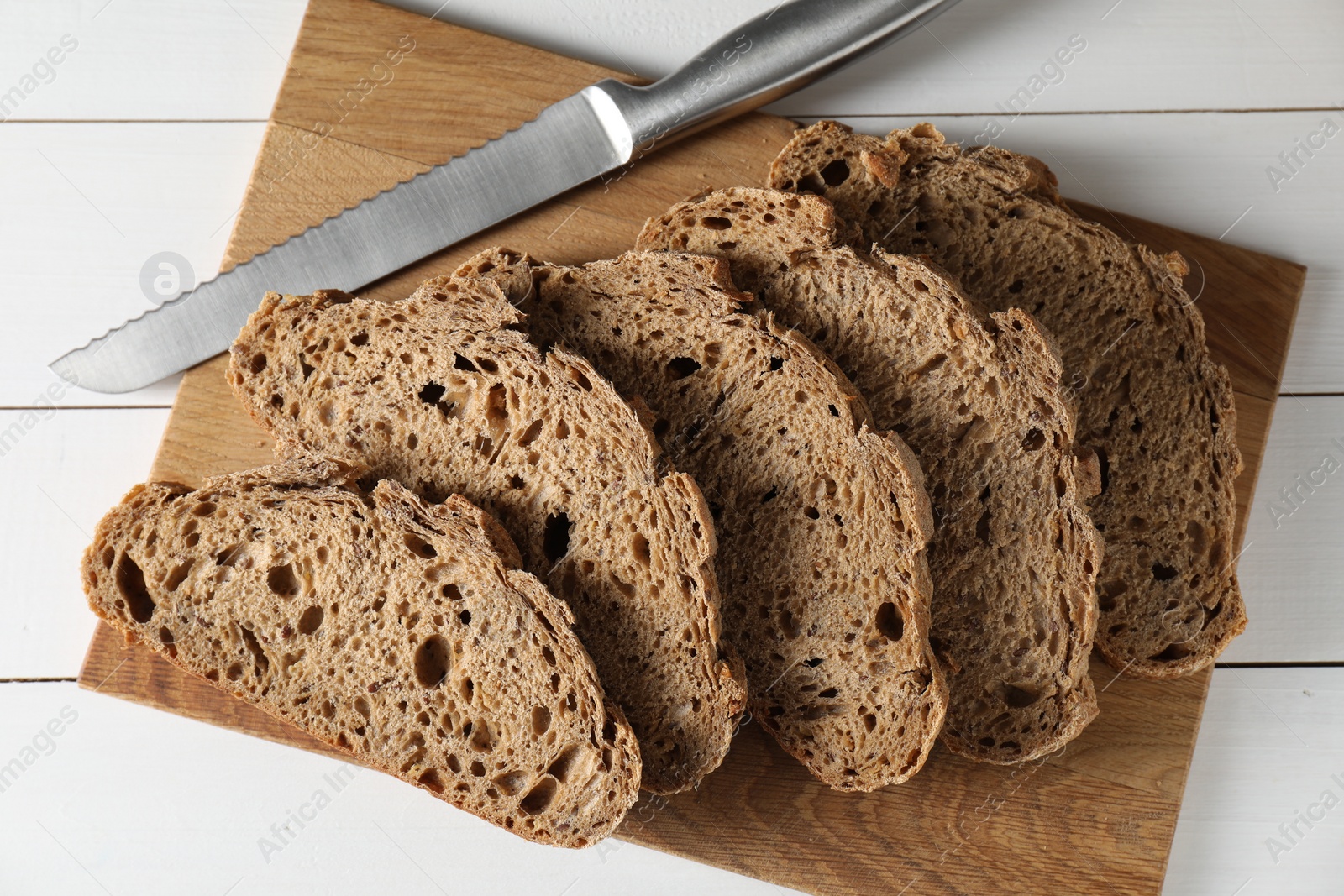 Photo of Freshly baked cut sourdough bread on white wooden table, top view