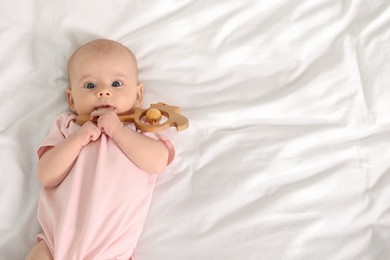 Photo of Cute little baby with toy on white sheets, top view. Space for text