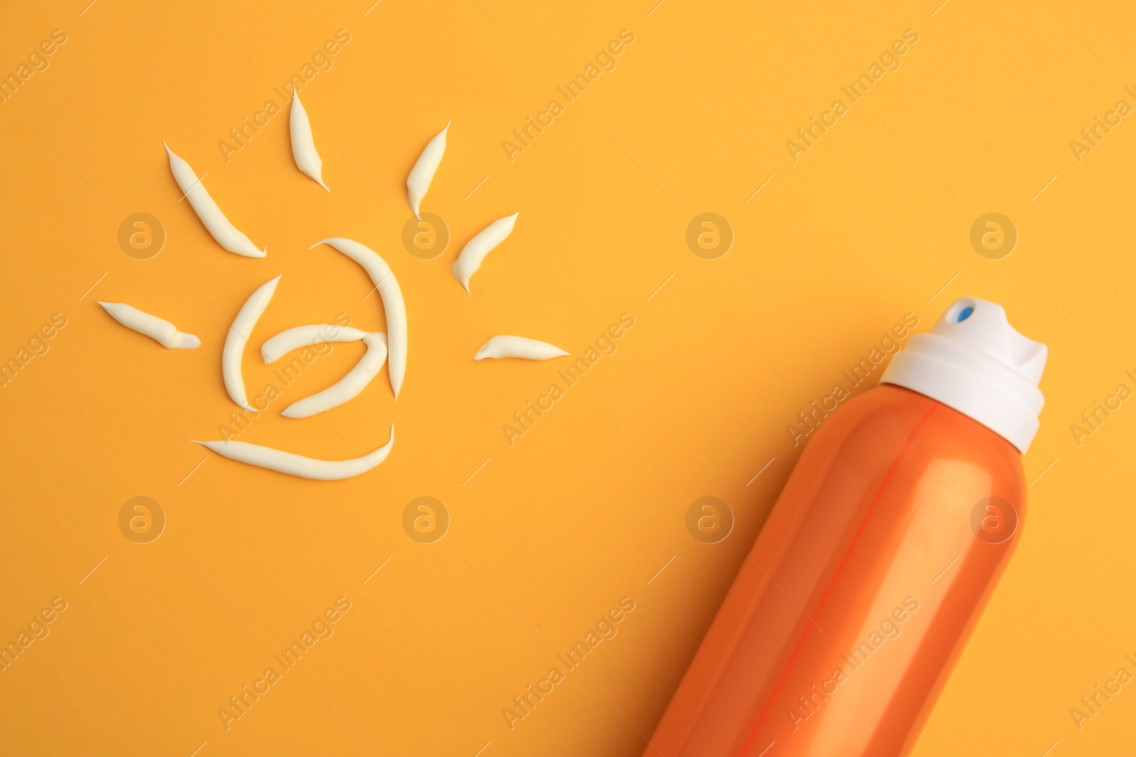 Photo of Drawing of sun and bottle with sunscreen on orange background, top view. Skin protection