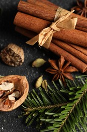 Photo of Different aromatic spices and fir branches on grey textured table, closeup