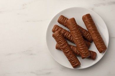 Photo of Sweet tasty chocolate bars on white marble table, top view. Space for text