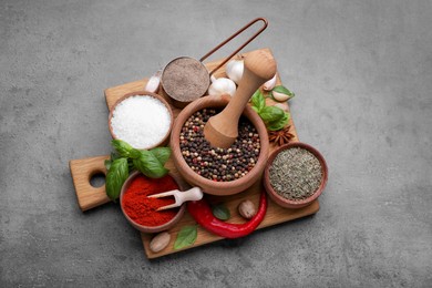 Photo of Mortar with different spices on grey table, above view