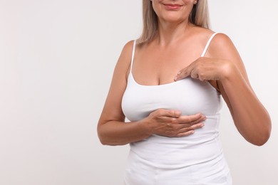 Woman doing breast self-examination on white background, closeup. Space for text