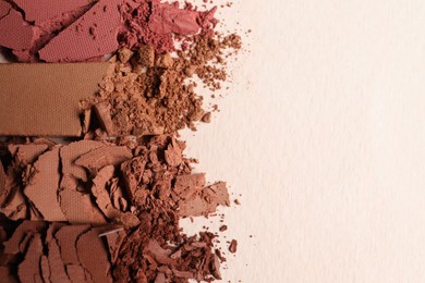 Different crushed eye shadows on beige background, flat lay. Space for text